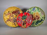 trois assiettes ornées de motifs différents, posées sur un support en métal