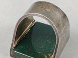 a close up of a silver ring with a green stone in it