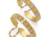 un gros plan sur deux bracelets en or sur fond blanc