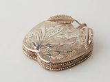 a small silver box with a leaf design on it