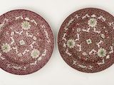 two red and white plates with floral designs on them on a white surface
