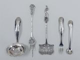 several silver spoons and forks are lined up on a white surface