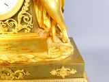 une statue en or représentant une femme tenant une horloge à la main