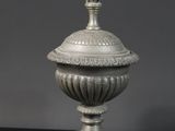 une urne en argent surmontée d'une figurine
