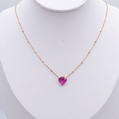 Un collier orné d'une pierre rose en forme de cœur est accroché à un mannequin