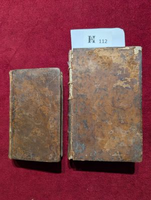 un vieux livre posé sur une surface rouge, à côté d'un petit bout de papier