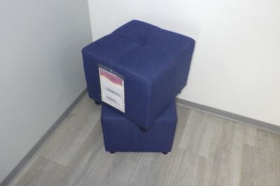 un petit tabouret bleu posé contre un mur blanc