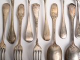a lot of silver spoons and forks on the table