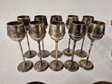 nine silver wine glasses lined up on a table