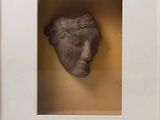 a close up of a sculpture of a face in a white frame