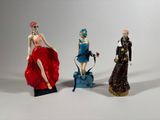 three figurines of women dressed in different styles and colors