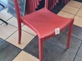 a red chair sitting in front of a stack of red chairs