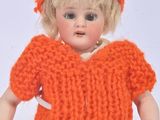 a doll that is wearing an orange sweater and hat