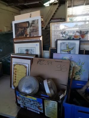 a pile of framed pictures on a table in a room