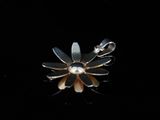 a close up of a flower shaped broochle on a black surface