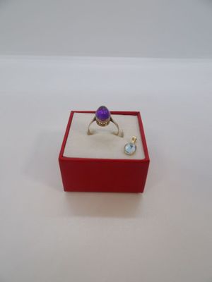 l'image d'un anneau violet dans une boîte rouge posée sur une surface blanche