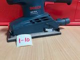 une ponceuse orbitale Bosch posée sur une table à côté d'une boîte rouge
