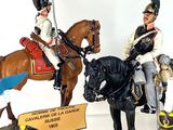 several figurines of men in uniforms riding horses and holding signs