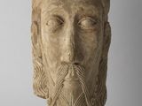 une tête en pierre représentant un homme barbu aux cheveux longs et à la barbe longue