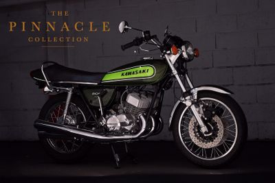 a green motorcycle parked in front of a brick wall