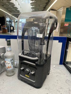 un mixeur posé sur un plan de travail, à côté d'une bouteille de vodka