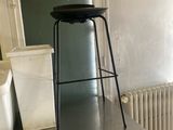 une table en métal sur laquelle est posé un tabouret, dans une pièce