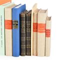 several books are stacked on top of each other on a white surface