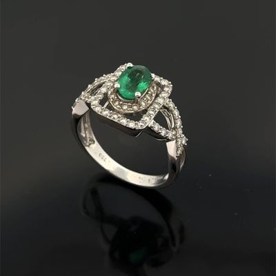 an emerald and diamond ring on a black surface