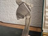 a silver sculpture of a woman holding an accordion