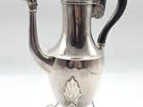 an antique silver teapot with a black handle on a stand