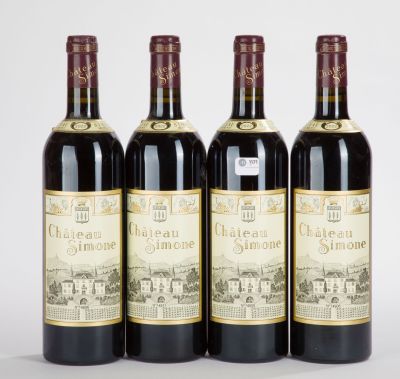 quatre bouteilles de vin sont alignées sur une surface blanche