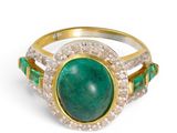 a close up of a ring with a green stone surrounded by diamonds