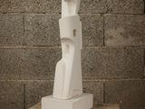 a white sculpture sitting on a wooden table in front of a brick wall