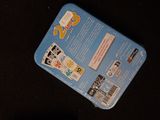 a blue tin with stickers on it sitting on a black surface