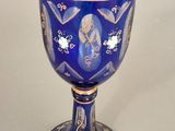 a blue glass with gold decoration on it on a table