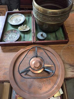 une casserole en cuivre posée sur une table en bois, sur laquelle se trouvent des assiettes et des bols