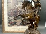 a bronze statue of a man on a horse with a flag