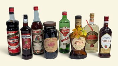 de nombreuses bouteilles d'alcool de toutes sortes alignées sur une surface blanche