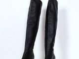 pair of black leather knee high boots on a white pedestal