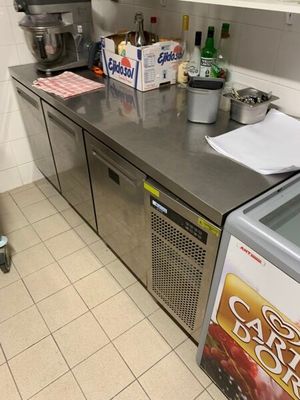 plan de travail en acier inoxydable dans une cuisine professionnelle équipée d'un réfrigérateur et d'un congélateur