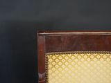 an old wooden chair with a yellow upholstered seat against a black wall