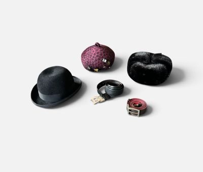 quatre chapeaux différents et une pince à chapeau posés sur une surface blanche