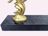 a gold statue of a woman holding a tennis racquet on a black marble base