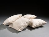 three white pillows sitting on top of a gray floor next to each other
