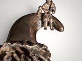 bronze figurine of a man riding a whale with a boy on it