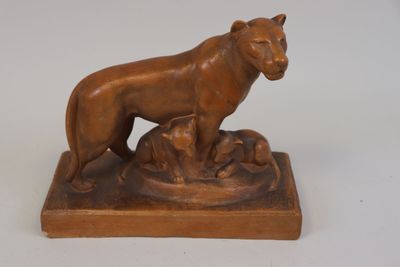 statue représentant un lion et un chien, posée sur un socle, sur une surface blanche