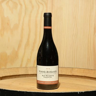a bottle of wine sitting on top of a barrel