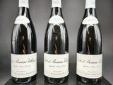 trois bouteilles de vin sont alignées sur une boîte noire