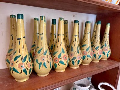 Des vases jaunes sont alignés sur une étagère en bois dans une pièce