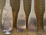 four silver spoons with designs on them sitting on a table